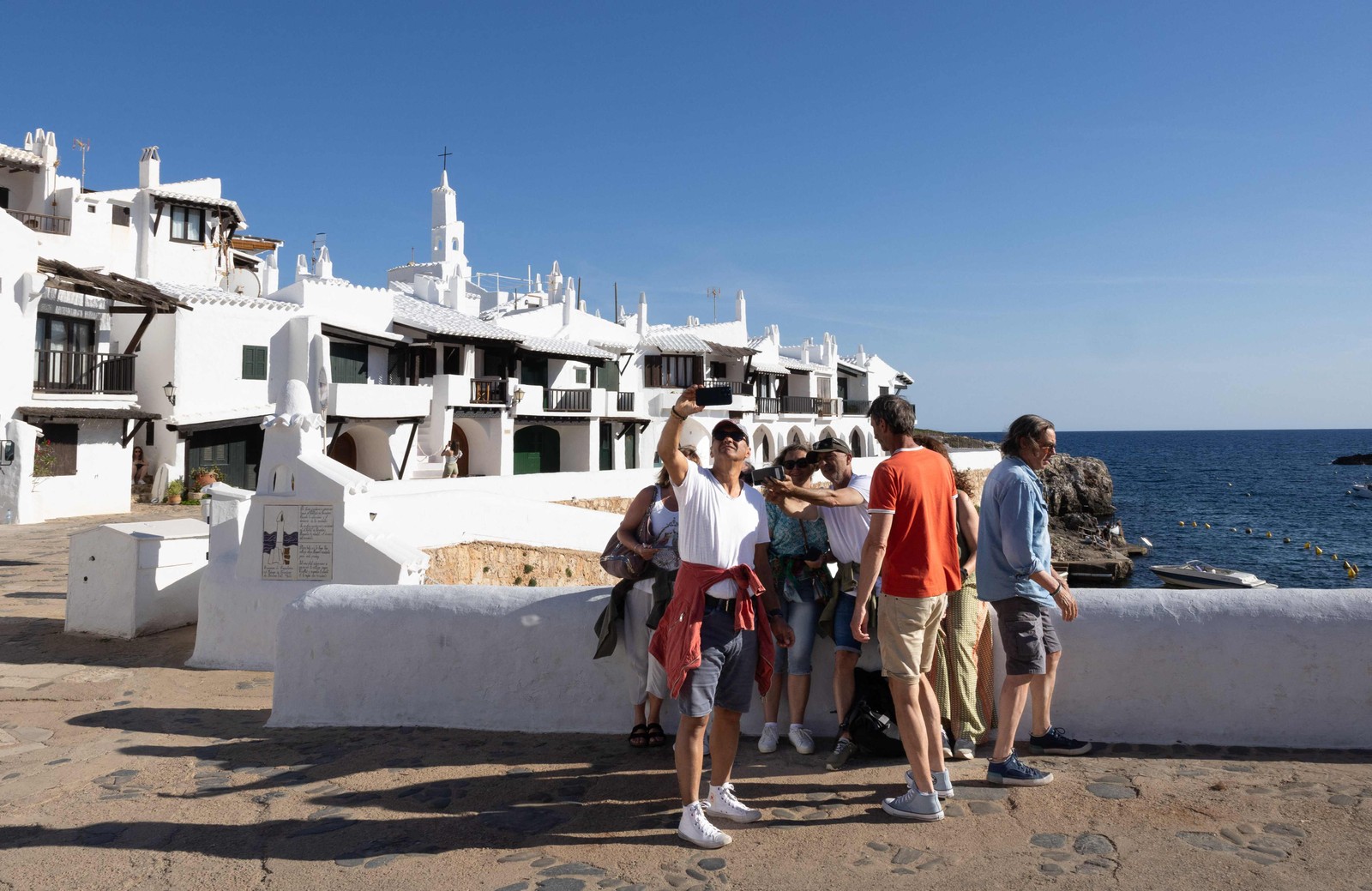 Grupo de turistas posa para foto em Binibeca Vell, o vilarejo na ilha de Menorca que ficou conhecido como 'Mykonos da Espanha' — Foto: Jaime Reina / AFP
