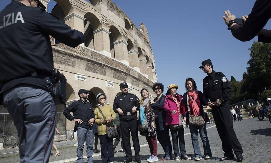 Turistas chineses posam para foto em frente ao Coliseu de Roma