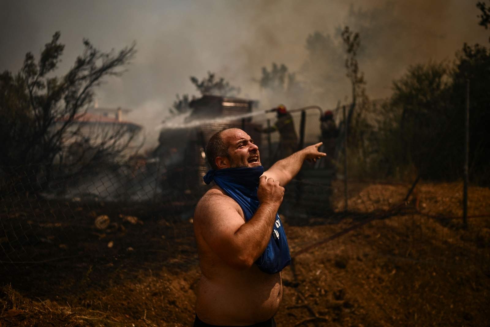 Um homem pede ajuda durante um incêndio florestal em Chasia, nos arredores de Atenas — Foto: Angelos Tzortzinis/AFP