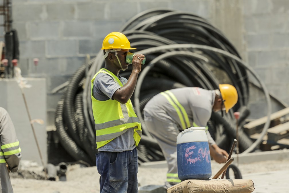 Nas obras do Terminal Gentileza, no final da avenida Brasil, no Rio, operários se hidratam sob forte calor — Foto: Gabriel de Paiva/Agência O Globo