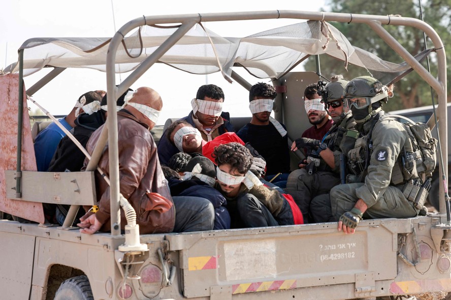 Soldados israelenses transportam palestinos, detidos durante a guerra, de Gaza para Israel.