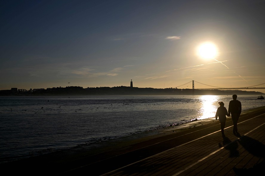 Casal caminha à beira do Rio Tejo, em Lisboa