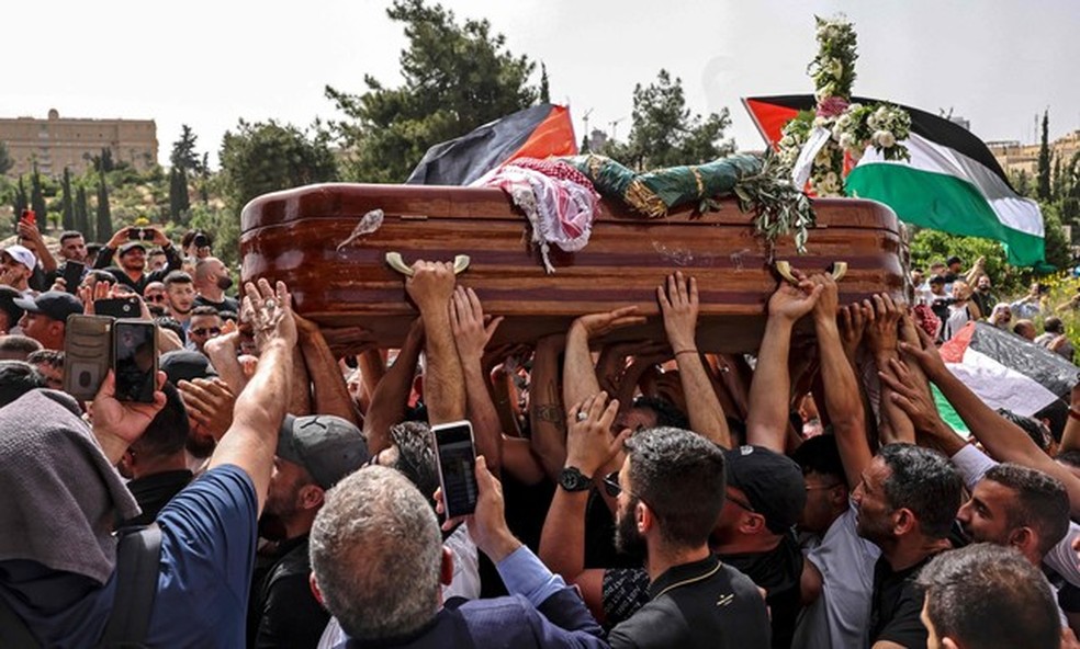Palestinos carregam o caixão da jornalista assassinada da Al-Jazeera Shireen Abu Aklel de uma igreja em direção ao cemitério, durante seu cortejo fúnebre em Jerusalém — Foto: RONALDO SCHEMIDT/AFP