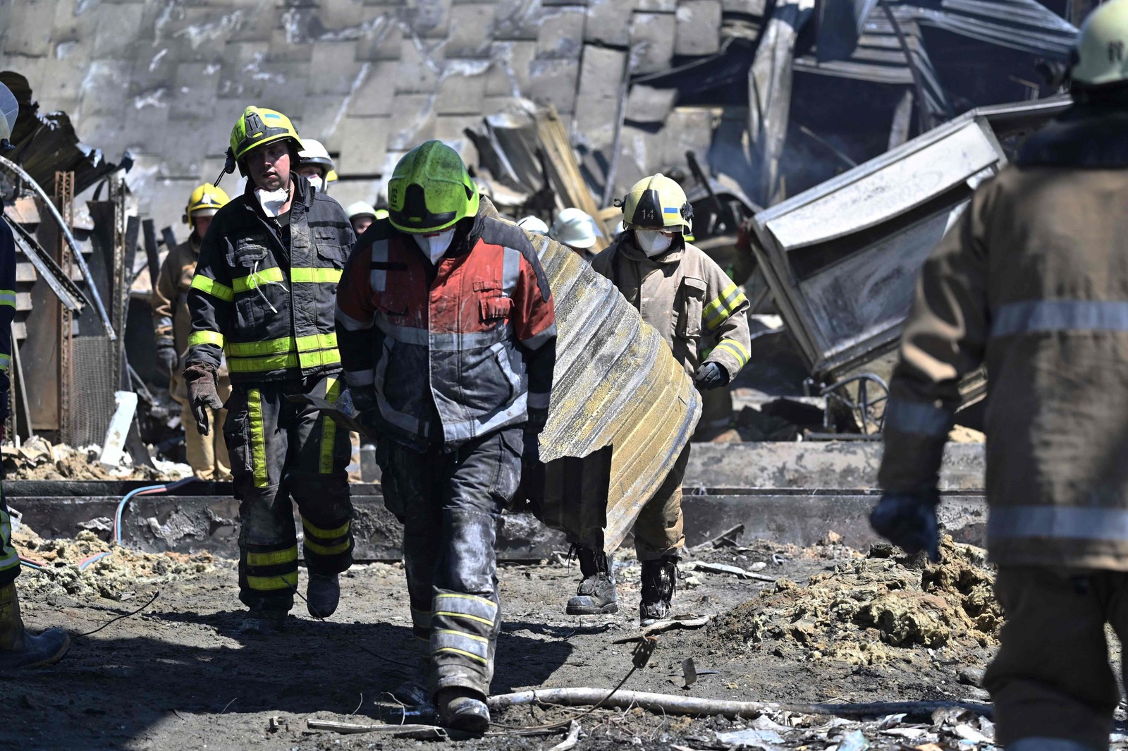 Trabalhadores fazem a limpeza dos escombros do shopping Amstor, um dia depois de ter sido atingido por um ataque de míssil russo, em Kremenchuk, na Ucrânia — Foto: GENYA SAVILOV / AFP