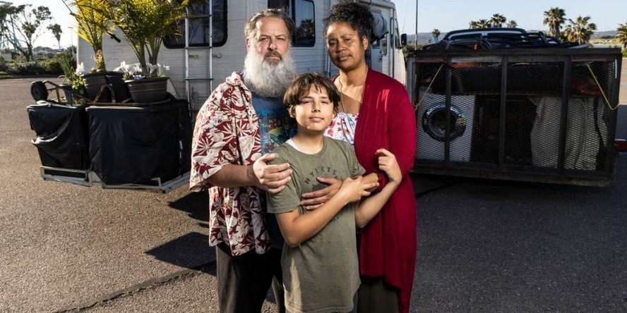 Chris Endres e Julienna Endres posam com seu filho Ayden na frente de seus veículos, que também são sua casa, em um estacionamento em San Diego, Califórnia