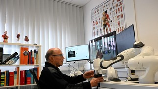 Médico Guenter Steinebach trabalha com o auxílio de um robô — Foto: Christof STACHE / AFP