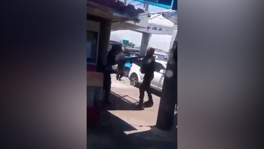 Imagem mostra momento em que policial aponta fuzil para um homem durante o protesto de moradores do Complexo da Maré
