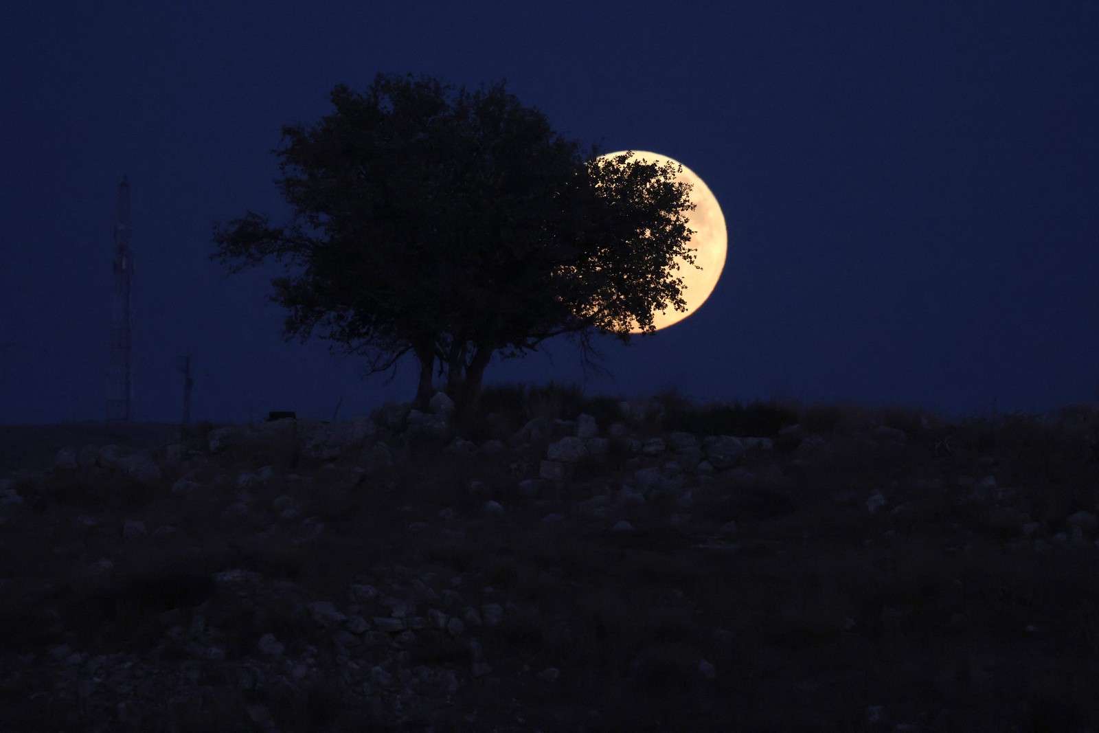 Uma foto tirada na cidade israelense de Rosh Haain mostra a ‘Lua Azul’ surgindo sobre a Cisjordânia — Foto: Menahem KAHANA / AFP