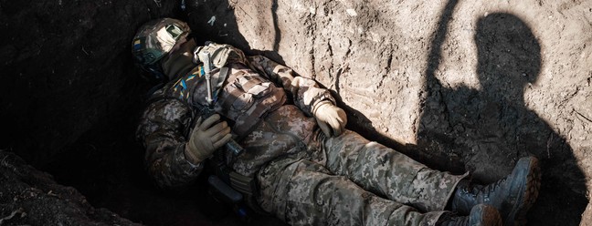 Soldado ucraniano descansa em trincheira recém-cavada enquanto companheiros disparam contra posição rua próximo em Bakhmut — Foto: YASUYOSHI CHIBA/AFP