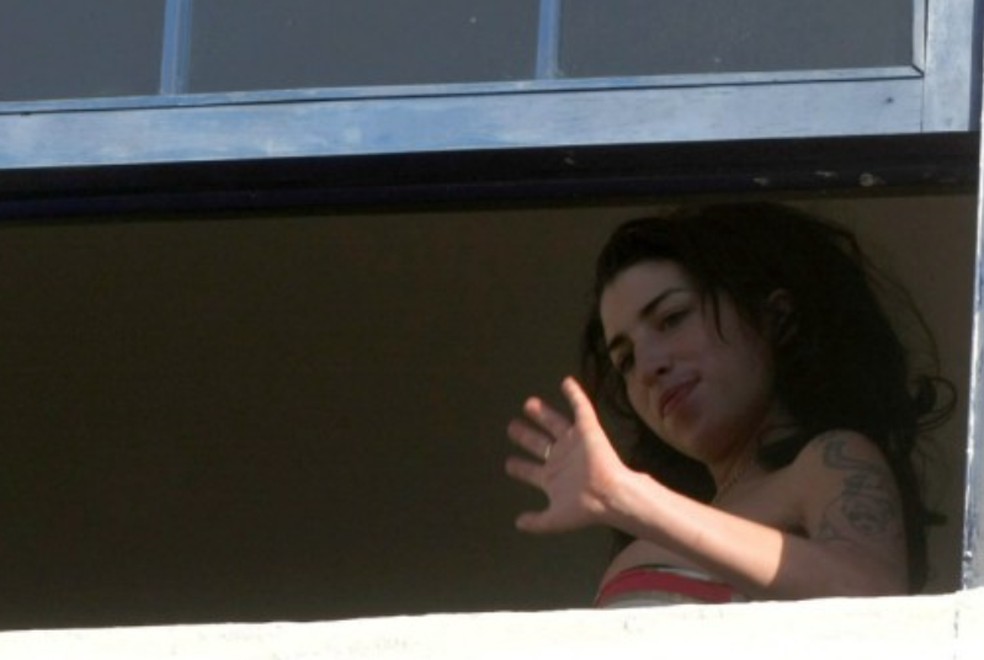 Amy Winehouse acena da janela do hotel no Rio — Foto: Marcelo Piu/Agência O GLOBO
