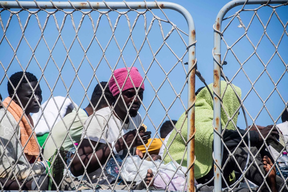 Migrantes se reúnem no convés do navio militar italiano Cassiopea, no porto da ilha italiana de Lampedusa, antes de serem transferidos para Porto Empedocle, na região da Sicília, sul da Itália — Foto: Alessandro Serrano/AFP