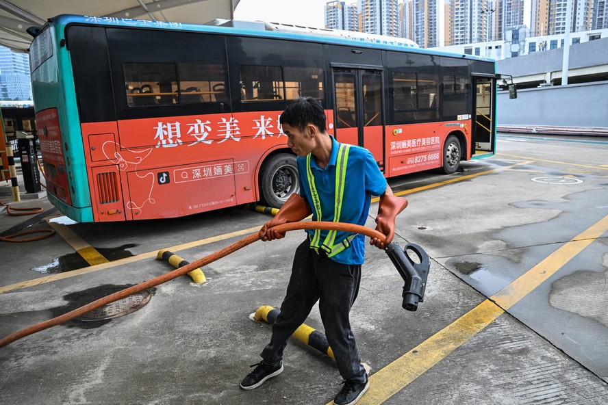 Funcionário se prepara para carregar um ônibus elétrico na estação de carregamento de Antuoshan, em Shenzhen
