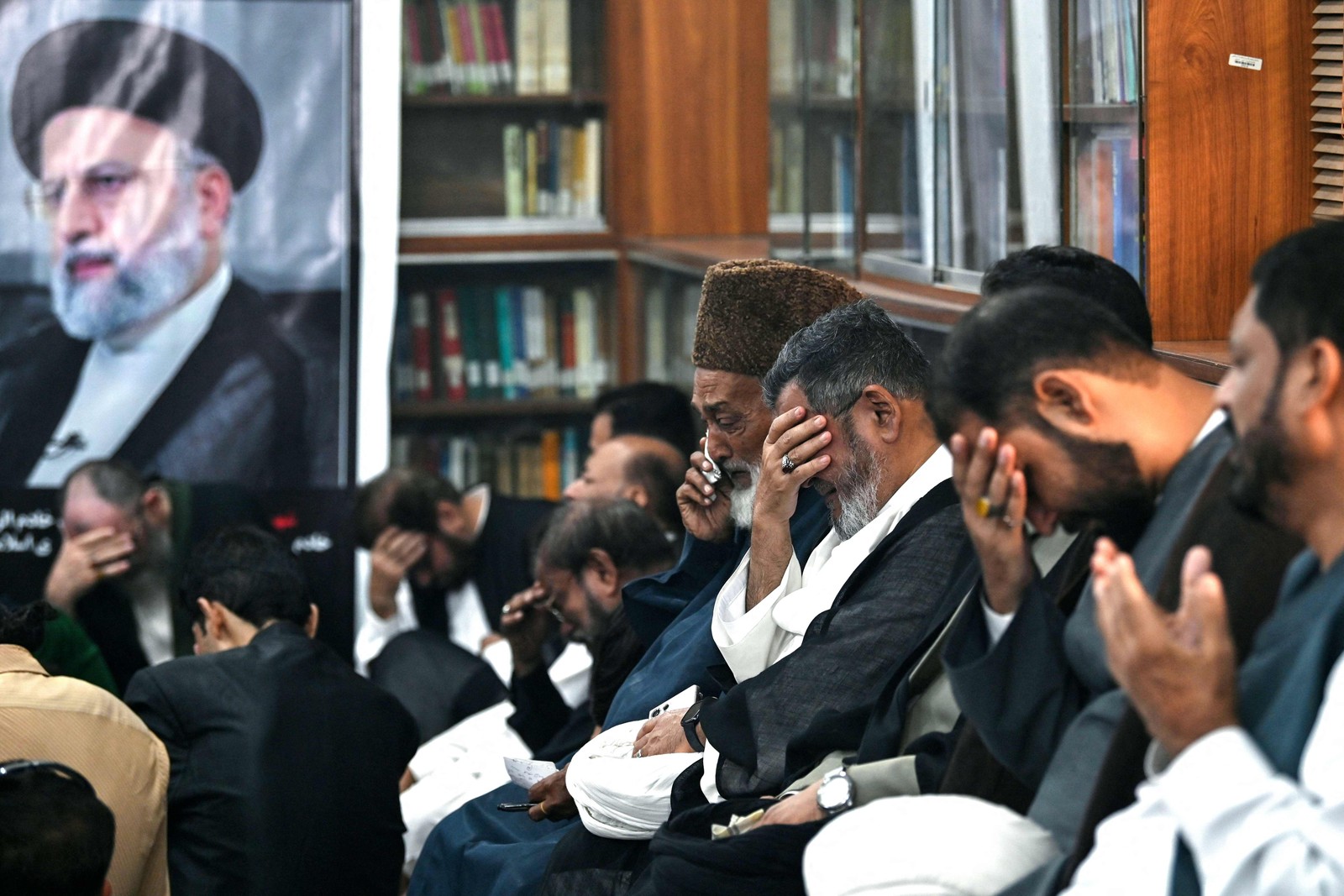 Pessoas lamentam a morte do presidente do Irã, Ebrahim Raisi, em um acidente de helicóptero, durante uma cerimônia de condolências no Centro Cultural do Irã, em Karachi. O primeiro-ministro do Paquistão, Shehbaz Sharif, declarou um dia de luto depois que a mídia iraniana informou que o presidente Ebrahim Raisi havia morreu em um acidente de helicóptero. — Foto: Asif HASSAN/AFP