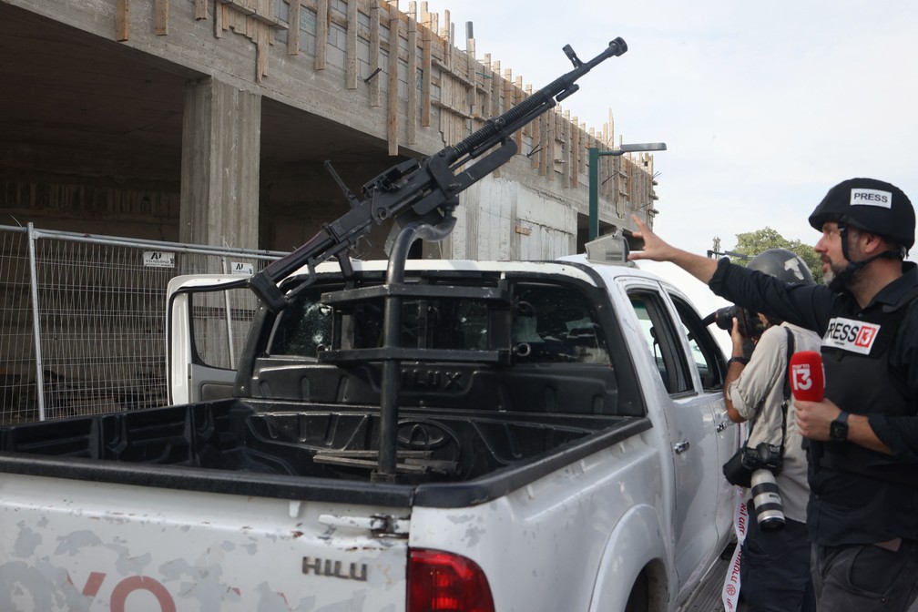 Jornalistas fazem todos de uma caminhonete usada pelo Hamas nos primeiros ataques a Israel. na cidade de Sderot — Foto: Oren ZIV / AFP