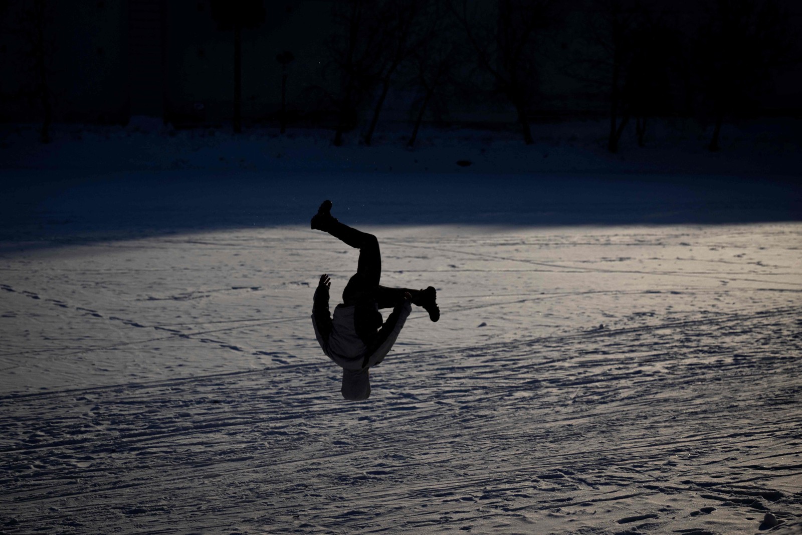 Menino realiza um salto mortal em um lago congelado em Moscou — Foto: Natalia KOLESNIKOVA / AFP