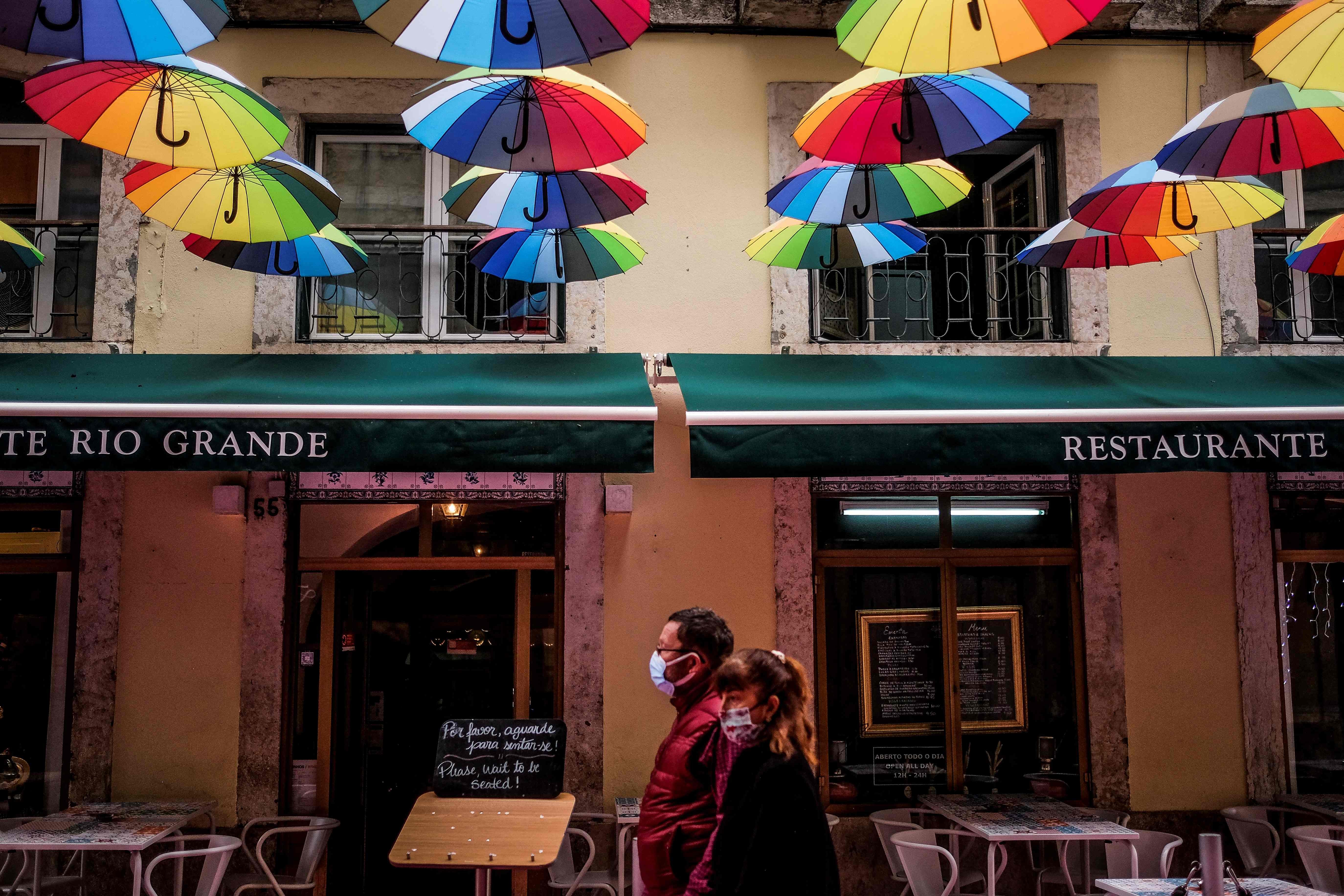 Pedestres caminham diante de restaurante em Lisboa