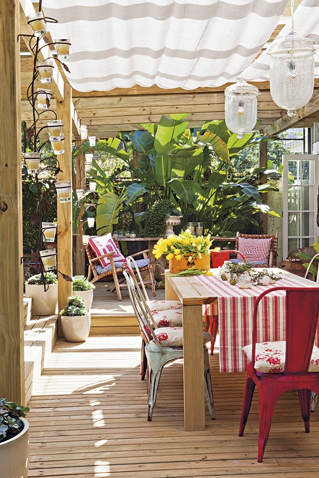 Utilizada para refeições mais demoradas e especiais, a mesa de jantar do terraço tem cadeiras de latão com almofadas florais. Molheiras trazidas de um antiquário em Punta del Este são usadas como vasinhos para os tostões. A caixa de vinho, à esquerda, virou cachepô para as tulipas. Casa da produtora de eventos Lica Paludo (Foto:  Lufe Gomes/Casa e Jardim)