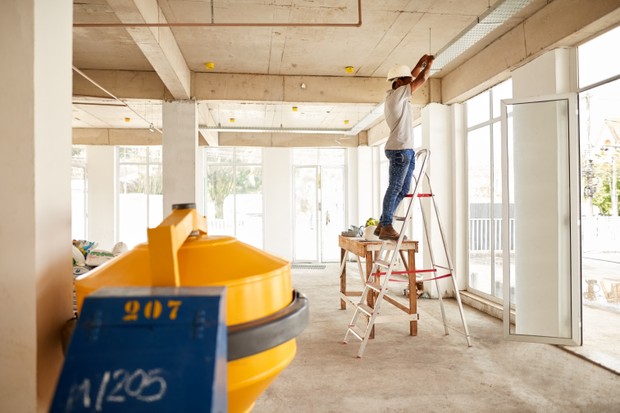 Shot of a construction worker doing electrical wiring installations on over hanging tray (Foto: Getty Images)