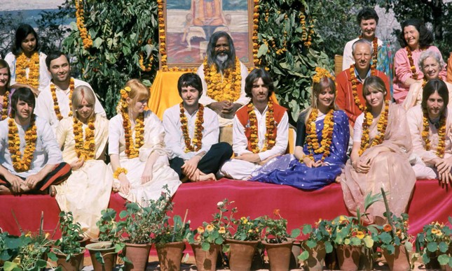 Os integrantes dos Beatles em meio a acompanhantes em centro de meditação na Índia