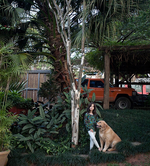 Teodora, filha da arquiteta Kita Flórido, ao lado do seu cachorro de estimação e da árvore pau-ferro, localizada no jardim de sua casa. Espaços assim são ótimos para cães de grande porte (Foto: Pedro Abude / Editora Globo)