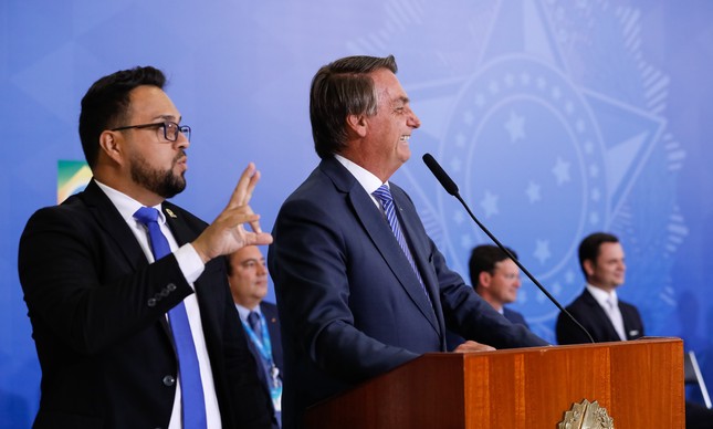 O presidente Jair Bolsonaro com o presidente da Caixa, Pedro Guimarães, e os ministros João Roma e Anderson Torres ao fundo