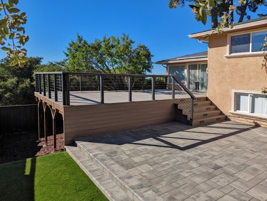 Photo of GCSF Pavers & Landscape - Burlingame, CA, US. Composite deck with cable railing and and step lights. Pavers and bullnose coping. Artificial turf. Mulch.