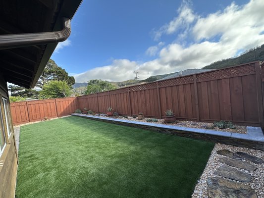 Photo of Earthtones - Pacifica, CA, US. Pacifica backyard lawn converted to artificial turf with succulent garden and natural stone retaining wall planter