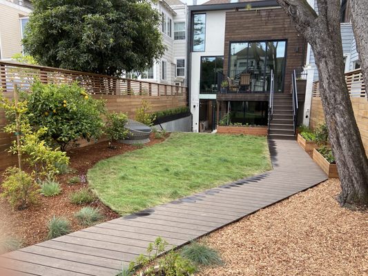 Photo of Logiculture - San Francisco, CA, US. Along the concrete retaining wall we installed an elevated planter. The lighter mulch is a playground chip awaiting a playhouse installation