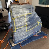 The piano is protected with blankets, shrink-wrapped, and placed on its side on a piano board.