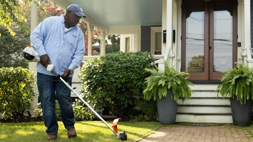 Lee Gilliam using a string trimmer to clean up a walkway