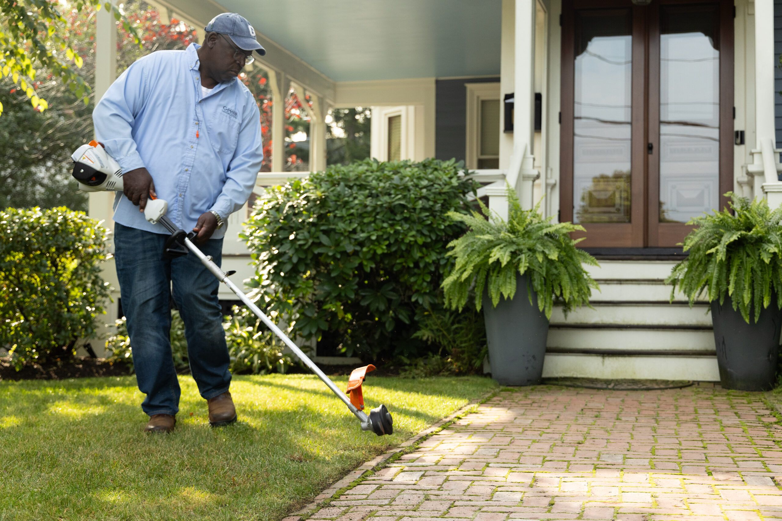 Lee Gilliam using a string trimmer to clean up a walkway