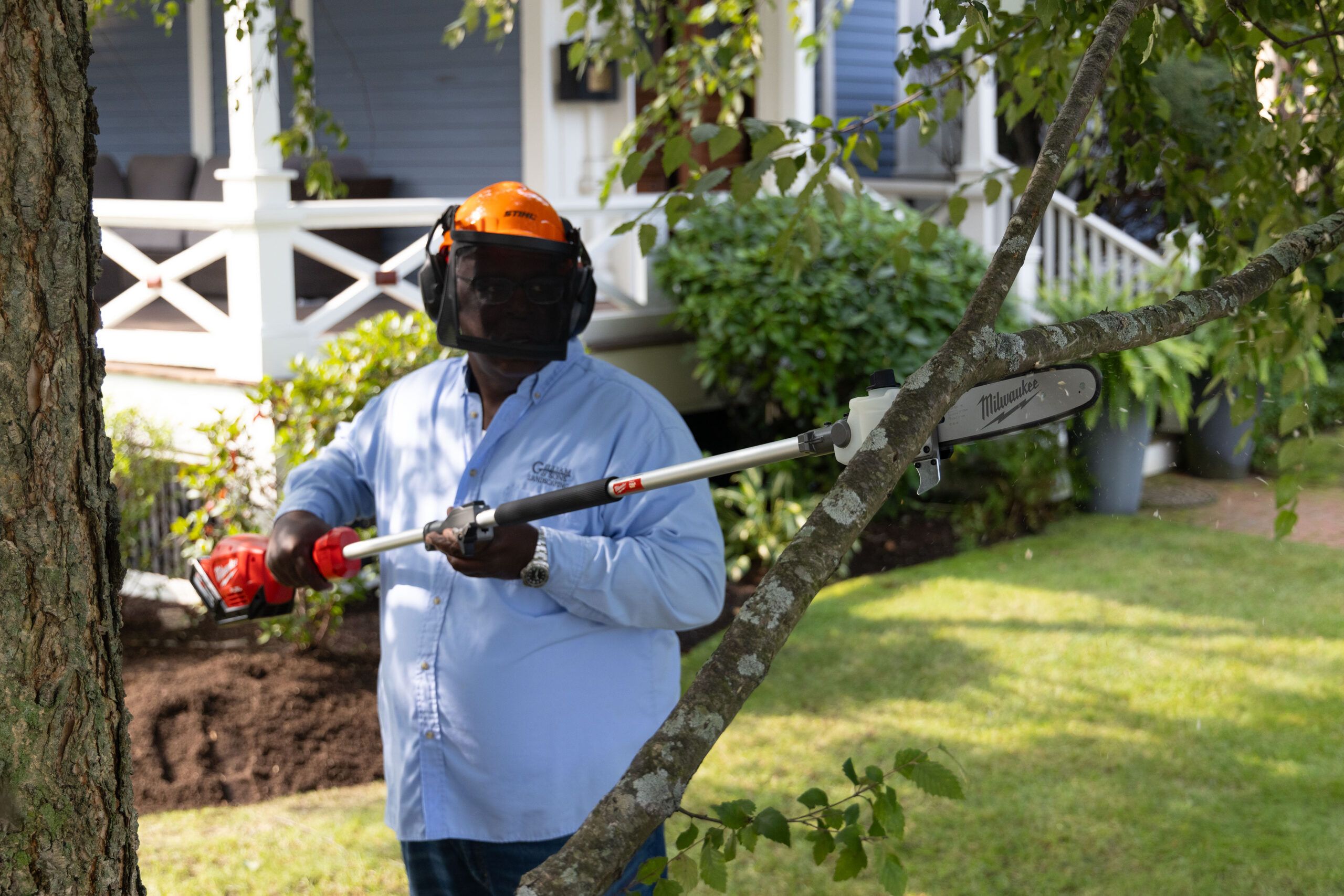 Lee Gilliam using a multihead tool to saw off a tree limb