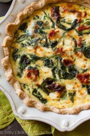 goat cheese spinach sun-dried tomato quiche in a white pie dish