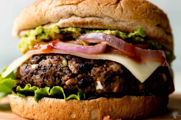 black bean burger with a bun, onions, cheese, lettuce, and avocado