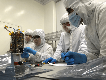 Photo of scientists in lab assembling equipment