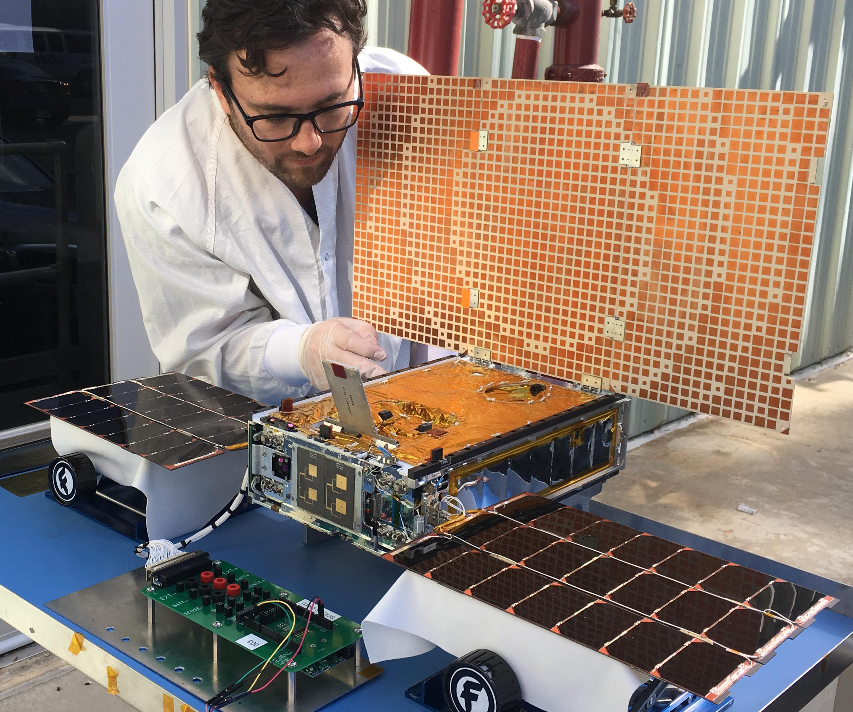 Man working on small spacecraft.