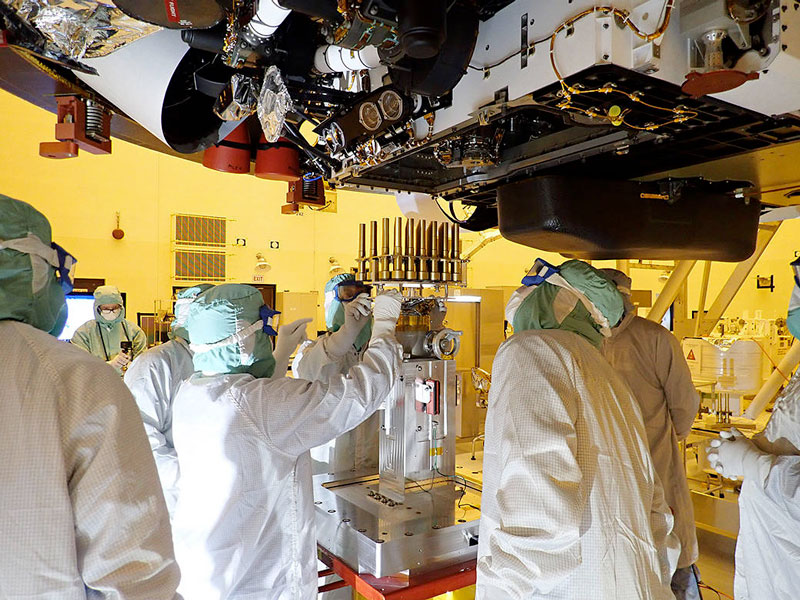 Engineers and technicians insert 39 sample tubes into the belly of the Perseverance rover. Each tube is sheathed in a gold-colored cylindrical enclosure to protect it from contamination. Perseverance rover will carry 43 sample tubes to the Red Planet's Jezero Crater.