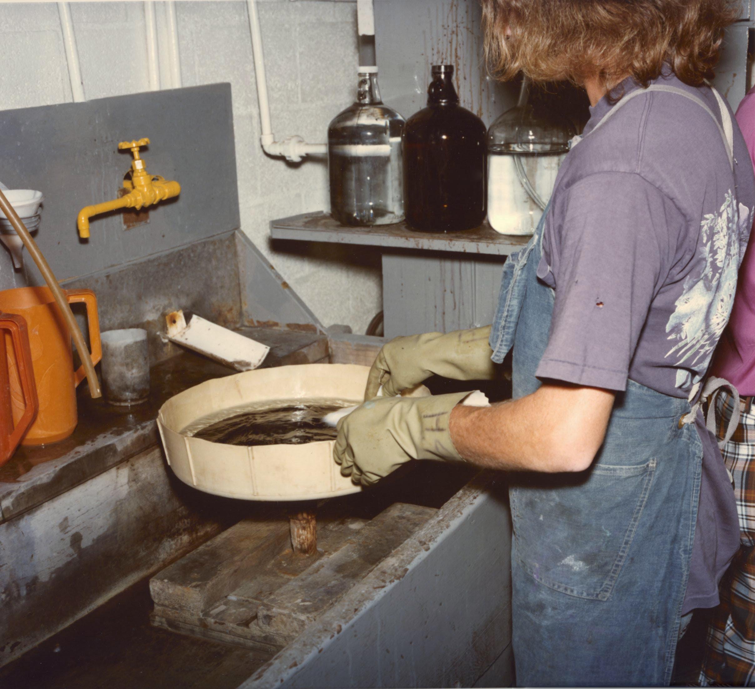 A woman dips a record in liquid.