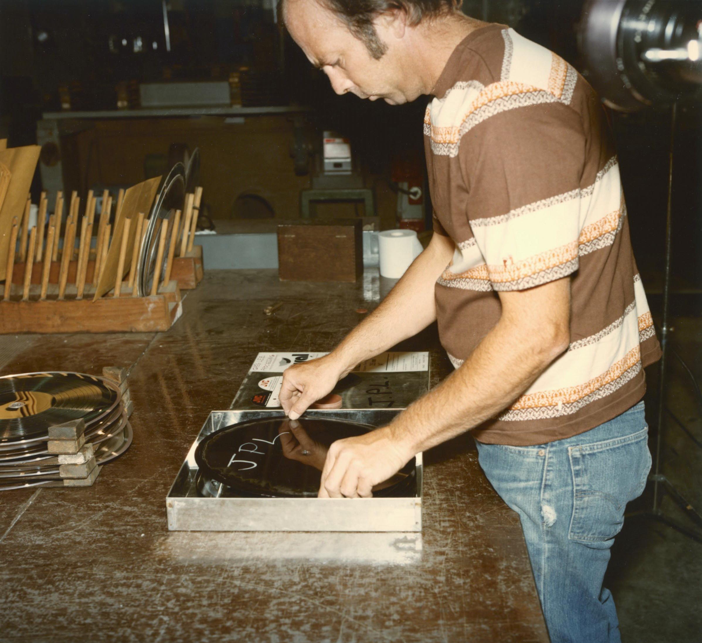 A man places a silver disc the size of a record in a tray.