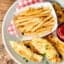 Chicken tenders on plate with fries and ketchup above