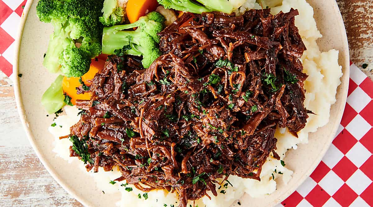 slow cooker flank steak over mashed potatoes with veggies above