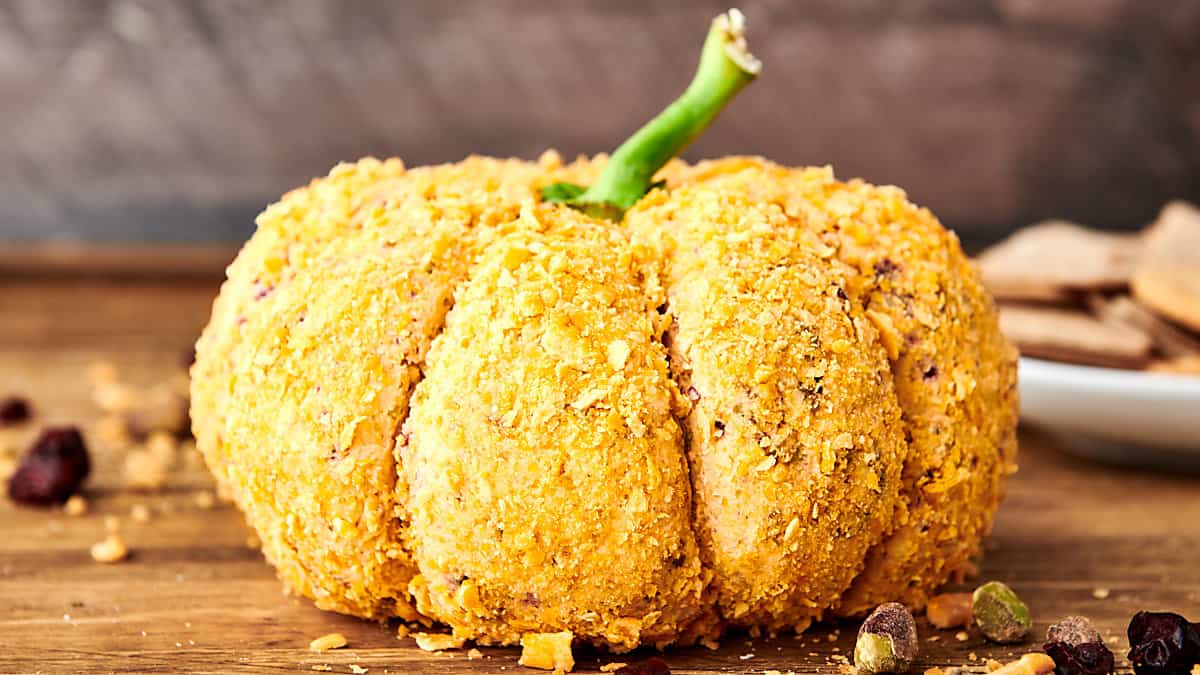 pumpkin spice cheese ball covered in crackers and topped with a bell pepper stem