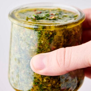 holding a glass jar full of chimichurri