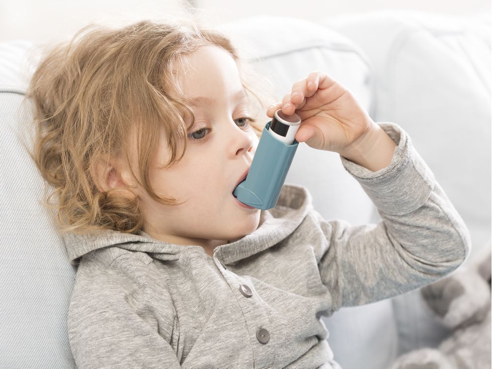 Small child using his inhaler device for asthma