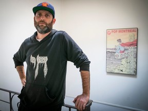 A man in a baseball cap and dark hoodie stands in front of a poster advertising the Pop Montreal festival.