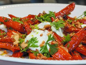 Maple-roasted carrots on a white plate, garnished with yogurt and parsley.