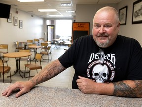 A man sits at a counter in a room that has several empty tables and chairs.