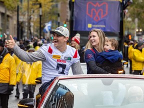 Cody Fajardo waves to the crowd sitting at the back of an open-top car