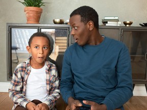 Father and son look shocked at something they've seen on a smartphone.