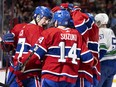 Canadiens' Kirby Dach, left, is seen smiling in a group hug with his teammates after scoring a goal at the Bell Centre in 2022.